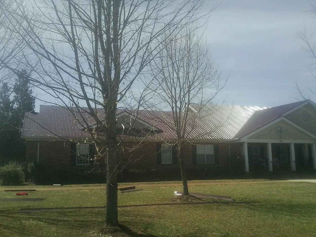 Red metal roof on a brick building seen from the front lawn in Huntingdon Valley