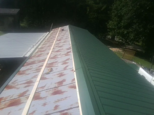 Old rusted panels beside newly installed green metal roofing — Wind Damage Roof Repair by Roofing Brothers in Huntingdon Valley