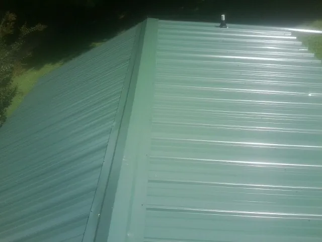 New green metal panels meeting at the ridge of a roof — Flat Roof Repair work by our crew in Huntingdon Valley