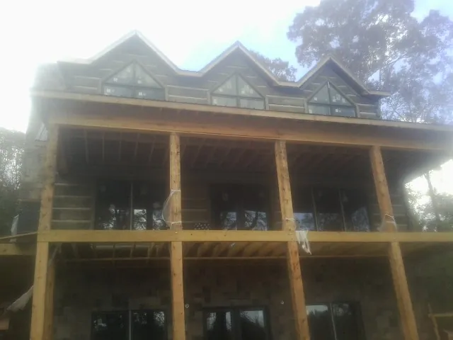 Dormers and porch framing on a large log home under construction — Roof Coating work by our crew in Huntingdon Valley