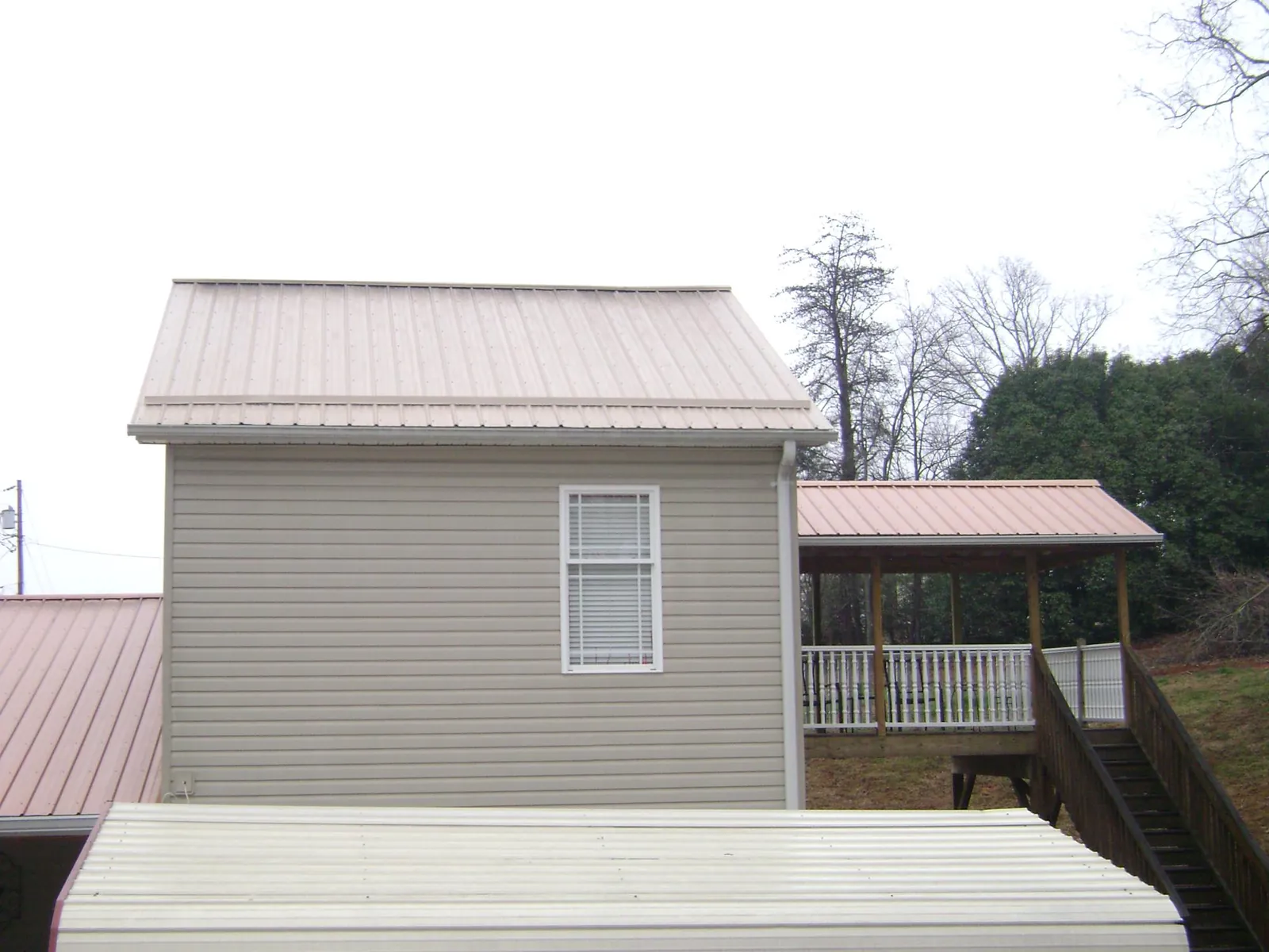 Tan metal roofs on a two story addition and attached porch, from a Roof Replacement job in Huntingdon Valley