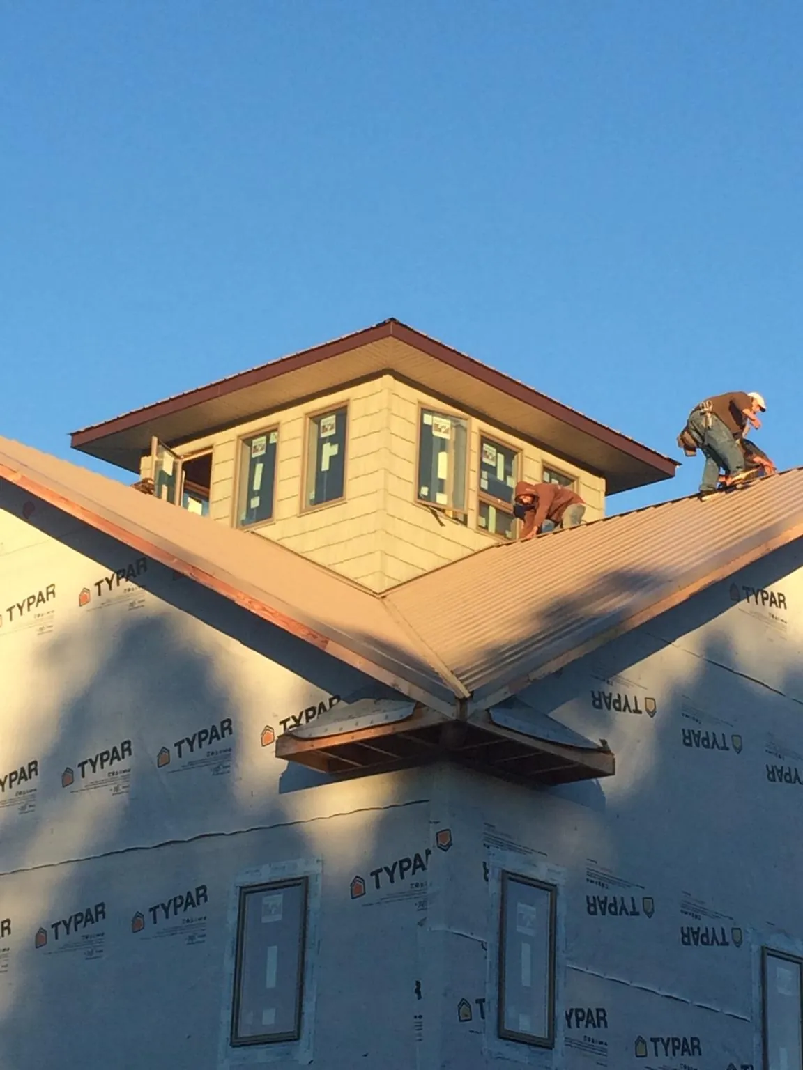 Roofers working around a rooftop cupola on a new metal roof at sunset — Roof Waterproofing in Huntingdon Valley by Roofing Brothers